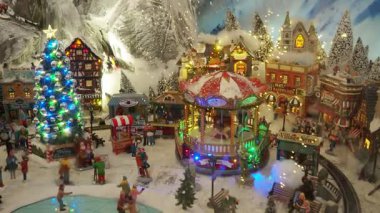 Minyatür tatil köyü ışıldayan ışıklar, neşeli figürler ve karla kaplı manzarayla canlanıyor, neşeli festival sezonu buluşmalarının özünü yakalıyor. Çocuklar için Noel ağacı gösterisi.