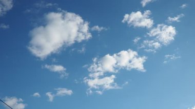 Yumuşak beyaz bulutlar canlı mavi bir ufuk boyunca zarif bir şekilde süzülür sakin bir öğleden sonra sükunet ve yansımayı davet eden sakin bir atmosfer yaratır. Gerçek zamanlı, ağır çekim gökyüzü