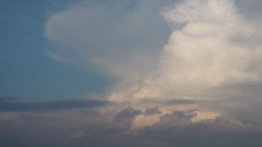Pofuduk, beyaz ve sarı bulutların çarpıcı görüntüsü canlı, mavi bir gökyüzüne karşı zarafetle süzülür. Güneş ışığı, bu güzel akşamda sakin bir atmosfer yaratarak dış hatlarını güçlendirir.