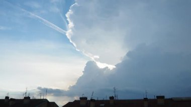 Güneşli akşam mavi gökyüzünde güzel beyaz bulutlar. Ses ötesi ışık efekti. Troposferde koruma. Gerçek zamanlı video. Antenli bir apartmanın çatısında. Gökyüzündeki kimyasal izler.