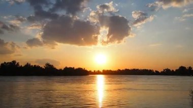 Güneş Sava Nehri üzerinde ufkun altında zarifçe batarken tanık büyüleyici bir dönüşüm geçiriyor. Günbatımını geciktirmek. Canlı renkler gökyüzünde dans ediyor, ağaçların siluetleri. Etkileyici bir fon. Sırbistan baharda.