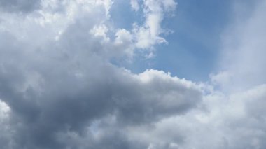 Pofuduk beyaz bulutların büyüleyici görüntüsü canlı mavi gökyüzünde sallanırken sakin bir atmosfer yaratır. Işığın ve gölgenin etkileşimi doğanın güzelliğini uyumda gösterir..