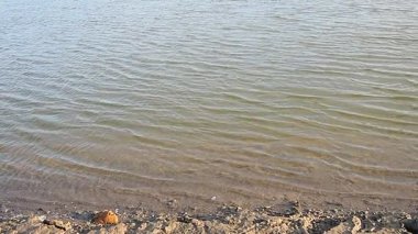 Yumuşak dalgalar, kıyı şeridinde yavaşça çekilirken büyüleyici desenler oluşturur. Sakin su yüzeyi, doğanın güzelliğini yansıtır. Ritm, cezbedici rahatlama. Suyun üzerinde yavaş dalgalanmalar