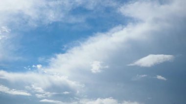 Tüylü beyaz bulutların geniş mavi gökyüzünde süzülmesi, fırtınaların gelişini işaret ediyor. Doğanın güzelliği renkler ve dokularla çelişiyor. Zaman aşımı.