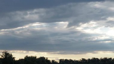 Alacakaranlık sırasında katmanlı bulutları parçalayan, sakin bir manzarada sanatsal özellikler sergileyen ışığın büyüleyici yolculuğuna tanık olun. Başımızda dönüştürücü bir görüntü beliriyor. Hızlı zaman aşımı.