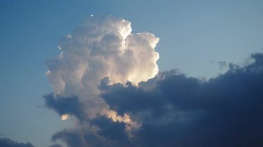 Gökyüzünde güzel beyaz bulutlar. Ses ötesi ışık efekti. Güneş ışınları yaklaşan kara bulutların arkasında gizlidir. Troposferde kümülüs konveksiyon. Cumulonimbus Günbatımı ve gün batımı. Zaman aşımı.
