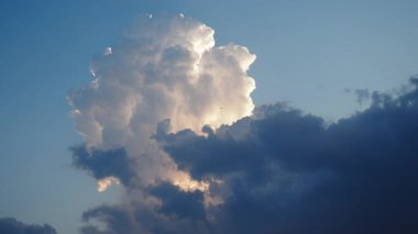 Gökyüzünde güzel beyaz bulutlar. Ses ötesi ışık efekti. Güneş ışınları yaklaşan kara bulutların arkasında gizlidir. Troposferde kümülüs konveksiyon. Cumulonimbus Günbatımı ve gün batımı. Zaman aşımı