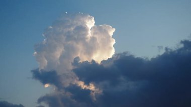 Canlı bir gökyüzü, gün batımının ılık renkleriyle yıkanmış tüylü beyaz bulutları sergiliyor, ufuk boyunca sakin bir ortam yaratıyor, rahatlama ve tefekkür için mükemmel. Zaman aşımı. Akşam şafağı