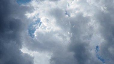 Yumuşak rüzgarlardan etkilenen kabarık bulutlar zarif bir şekilde gökyüzünde döner ve sürüklenir. Canlı mavinin arkaplanı bu sakin doğal görüntünün güzelliğini arttırır..