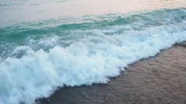 Karadağ 'ın Canj kentindeki Adriyatik Denizi üzerinde güneş yükselirken, kumlu kıyıya hafif dalgalar vuruyor. Huzurlu atmosfer, rahatlamaya ve altın sabah ışığını yansıtmaya davet eder..