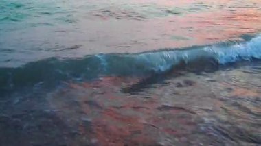 Karadağ 'ın Canj kentindeki kumlu sahilde hafif dalgalar sabah güneşini yansıtıyor. Sakin atmosfer ve sakin sular Akdeniz kıyısında mükemmel bir sahil manzarası yaratır..