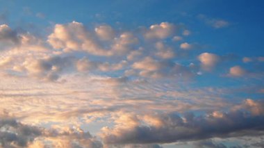 Sarı turuncu günbatımı gökyüzü bulutları. Yumuşak, ılık sarı renkler huzurlu ve huzurlu bir atmosfer yaratıyor. Batan güneşin hafif ışınları altın dokunuşuyla ufku boyuyor. Şehrin çatısında gün batımı. Gerçek zamanlı.