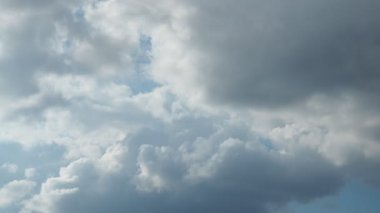 Pofuduk bulutlar parlak bir gökyüzünde sürükleniyor, mavi ve gri tonlarını sergiliyor. Bulutların dinamik hareketi atmosferik bir görüntü yaratır. Doğa aşıkları ve gökyüzü gözlemcileri için mükemmel..