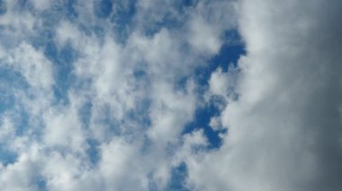 Güneşli bir öğleden sonra bulutlar parlak bir mavi gökyüzünde sürükleniyor, güzellikleri gözler önüne seriyor ve herkesin keyif alması için sakin bir atmosfer sağlıyor..