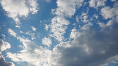 Parlak mavi gökyüzü zarafetle sürüklenen çeşitli bulut şekilleriyle doludur. Güneş ışığı kırılıyor, sakin bir atmosfer yaratıyor rahatlama ve doğa takdiri için mükemmel..