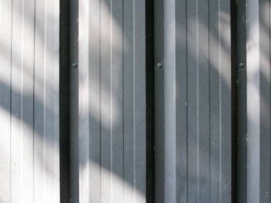 Güneş ışığıyla parlayan gri metal levha duvarının yüzey detayları dekoratif tasarım için soyut arka plan dokusu.