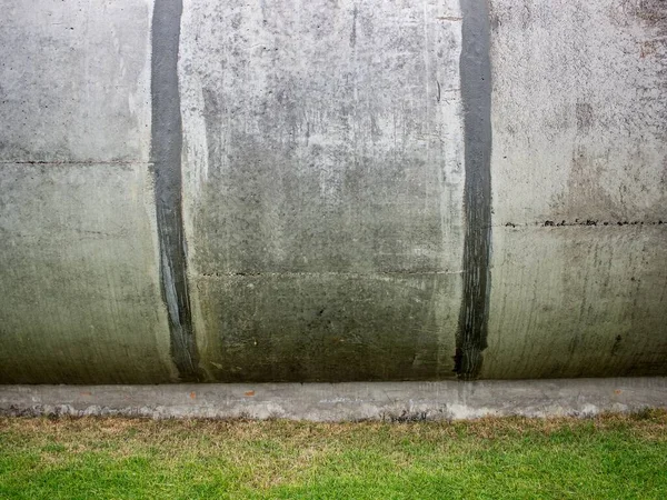 Çimenlikteki eski eğri beton duvar, dekoratif tasarım için soyut arkaplan.