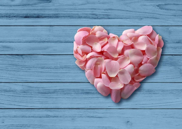 Above view Heart shaped of Light pink rose petals on blue sky wooden slat floor with clipping path.