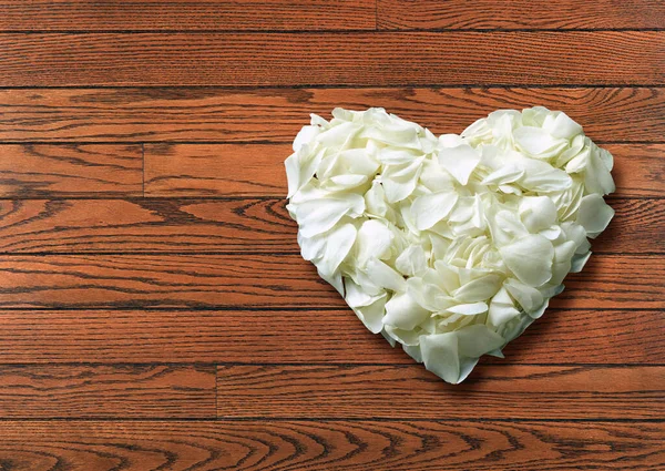 Above view Heart shaped of White rose petals on Wooden slat floor with clipping path.
