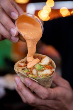 Çiotlu kremayı gevrek ve lezzetli tavuk dürümüne koyan kişi.