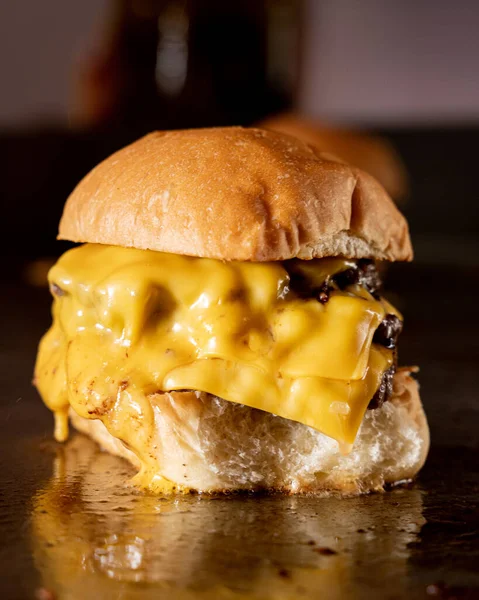 Delicious slider burger with lots of yellow cheese on a grill