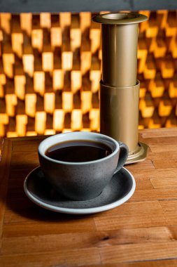 delicious coffee prepared with aeropress method, on a nice gray ceramic cup and a nice background, inside a coffee shop.
