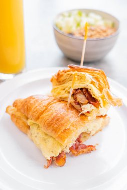 Delicious croissant with egg, bacon and accompanied with a fresh orange juice, perfect breakfast.