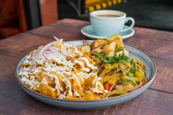 Delicious Mexican breakfast, red chilaquiles prepared with cheese and sour cream, accompanied with nopales and fried beans, perfect Mexican breakfast.
