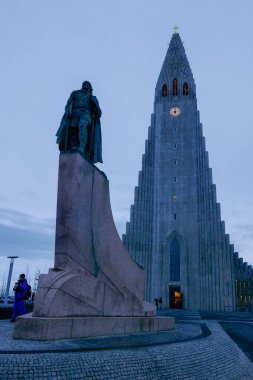 Hallgrimskirkja, yüksek kulesiyle Reykjavik siluetine hakim. Modern tasarımı, gün batımından sonra saatleri olan kilise kulesi.