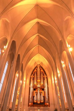 Hallgrimskirkja, yüksek kulesiyle Reykjavik siluetine hakim. Modern tasarımı, kilisenin içi sıcak sarı ışıkla kaplı.