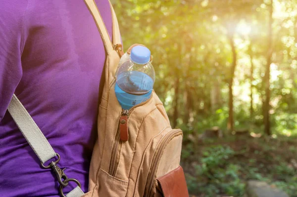 Drinking water bottle in women\'s backpack. Drinking water for hiking, traveling, daily activities