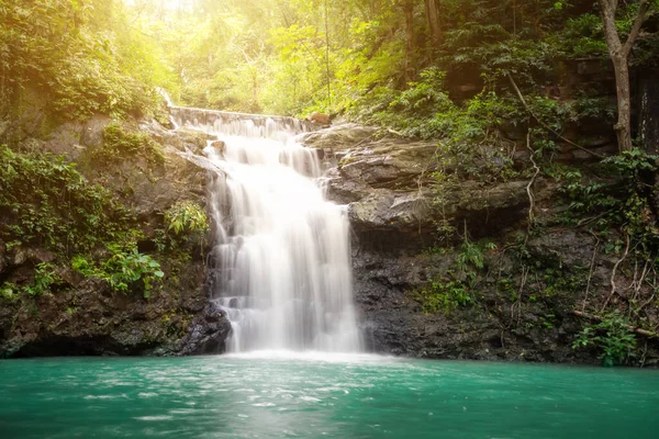 Small waterfall with water splashing and tumbling over the rocks in the forest on a bright sunny