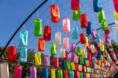 İçinde ampuller olan renkli kumaş fenerler geleneksel festivalde süslemek için asılıydı çatı çerçevesi güzel kumaş fenerlerle süslenmişti. Işıklar ve parlak renkler var.