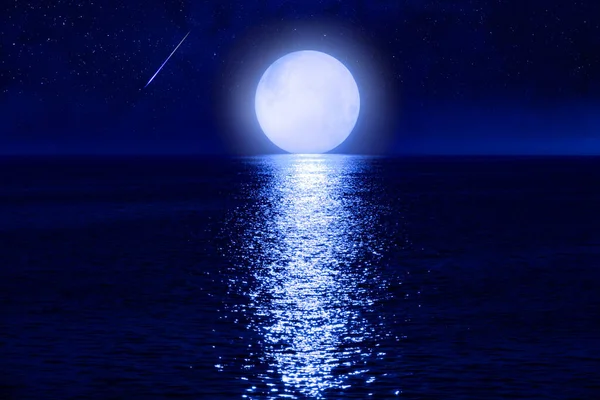 Full Moon with starry skies rising above ocean horizon.