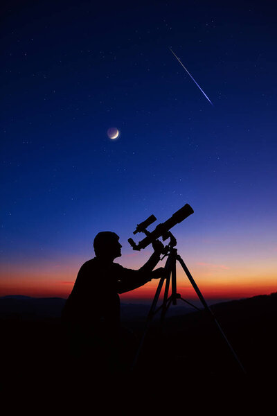 Man with astronomy telescope looking at the night sky, stars, planets, Moon and shooting stars.