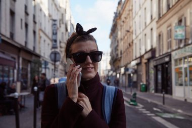 Paris sokaklarında akıllı telefon kullanan genç bayan..