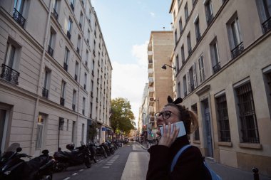 Paris sokaklarında akıllı telefon kullanan genç bayan..