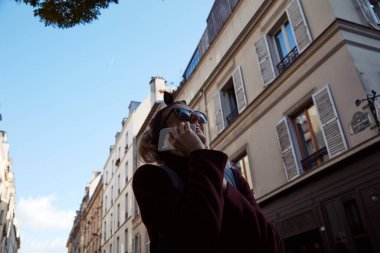 Young lady using smartphone on Paris streets.