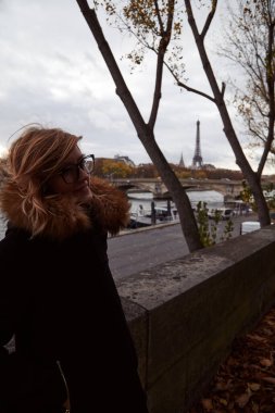 Genç bayan Paris, Fransa 'da Seine nehrinin kıyısında dışarıda eğleniyor. Arka planda Eyfel kulesi.