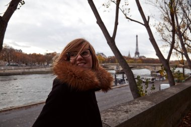 Genç bayan Paris, Fransa 'da Seine nehrinin kıyısında dışarıda eğleniyor. Arka planda Eyfel kulesi.
