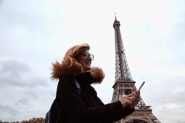 Young lady using smartphone on Paris streets.