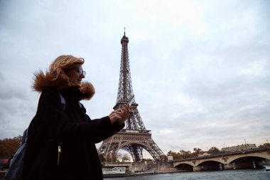 Young lady using smartphone on Paris streets.