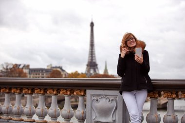 Young lady using smartphone on Paris streets.