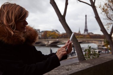 Young lady using smartphone on Paris streets.