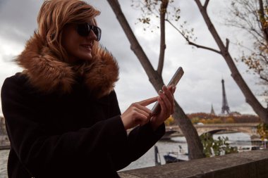 Young lady using smartphone on Paris streets.