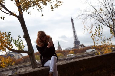 Paris sokaklarında akıllı telefon kullanan genç bayan..