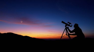Astronomi teleskopu olan adam gece gökyüzüne, yıldızlara, gezegenlere, aya ve kayan yıldızlara bakıyor..