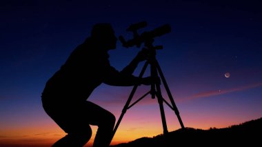 Astronomi teleskopu olan adam gece gökyüzüne, yıldızlara, gezegenlere, aya ve kayan yıldızlara bakıyor..