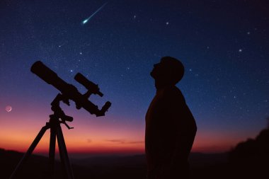Man with astronomy telescope looking at the night sky, stars, planets, Moon and shooting stars.