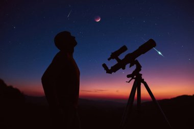 Man with astronomy telescope looking at the night sky, stars, planets, Moon and shooting stars.
